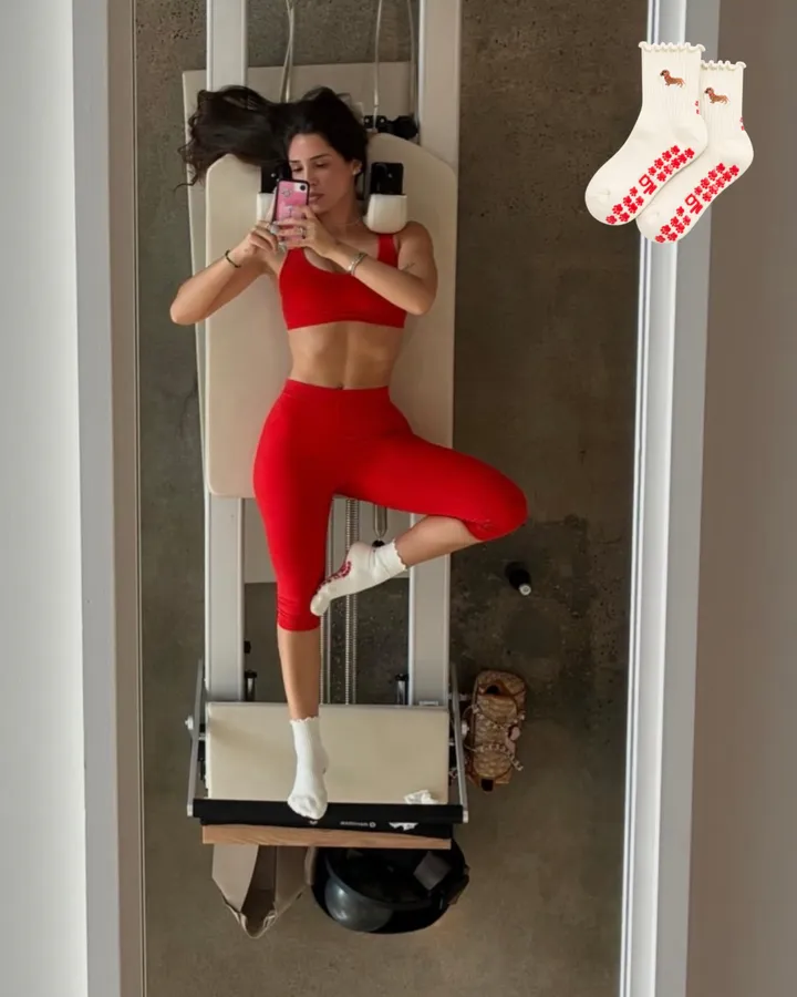 An overhead shot on a reformer wearing Doxie grip socks with a red set