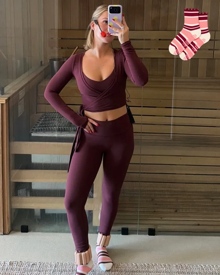 A mirror selfie in a burgundy set and raspberry striped grip socks with ankle weights