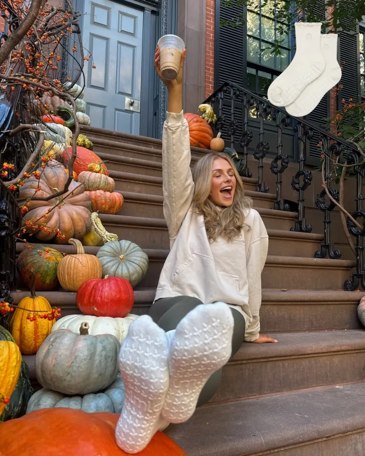 Sitting on brownstone steps among pumpkins, feet up in cream Oat Milk grip socks